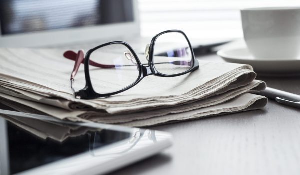 Newspaper with tablet on table